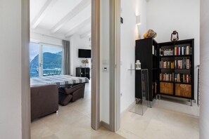 A modern bedroom with a bed, a bookshelf, and a view of the outdoors.