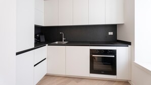 Een moderne keuken met witte kasten, een zwart aanrecht en een inbouwoven.