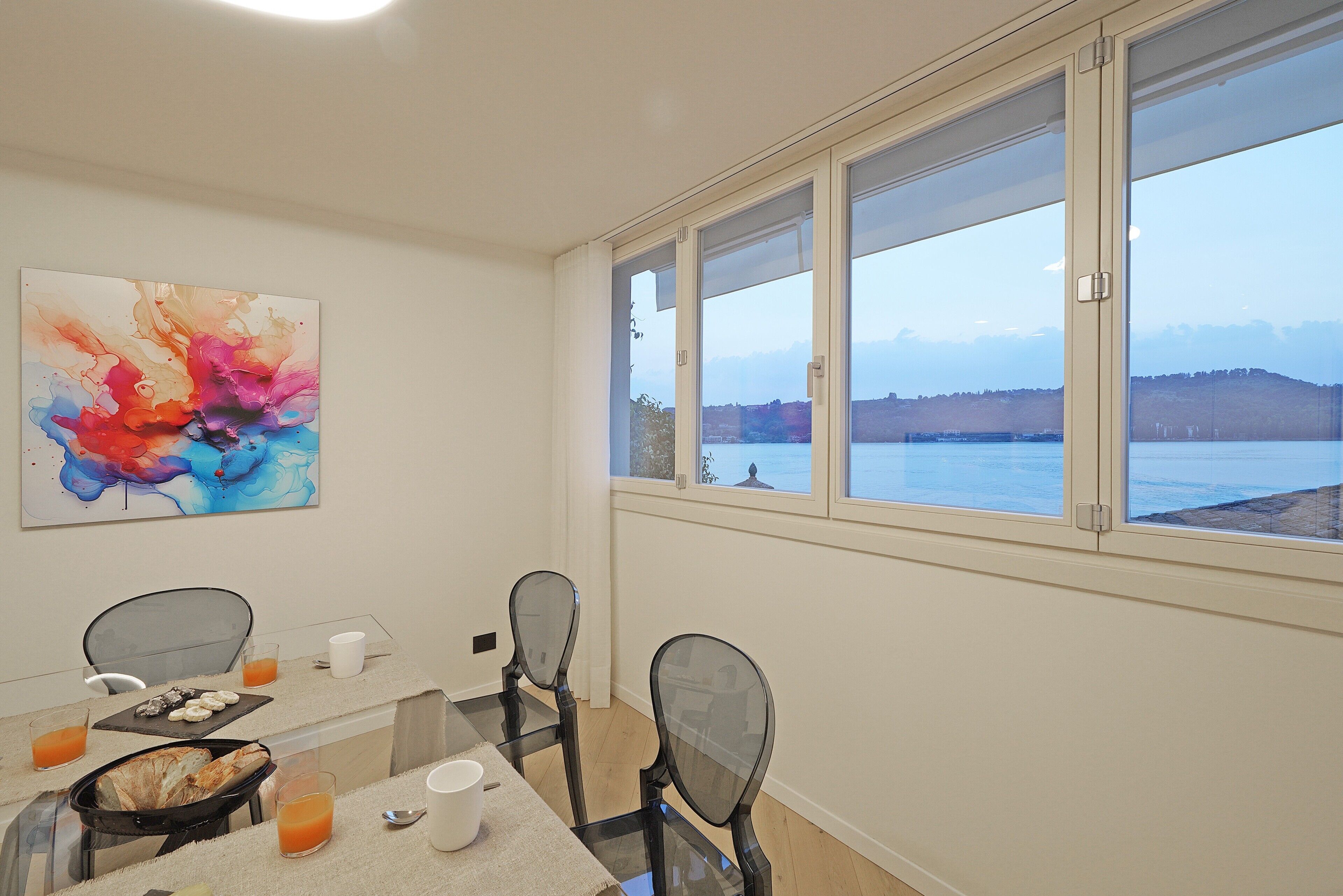A dining area with a table set for two, a glass partition, and a view of the sea.