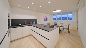 Een moderne keuken met een centraal eiland, een eethoek met een tafel en stoelen, en een raam met uitzicht.