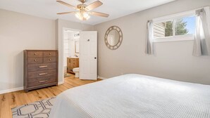 A bedroom with a bed, dresser, ceiling fan, and a view of the bathroom. - Mountain Retreat, Balcony, Grill, and 5 Minutes to Downtown! (Blowing Rock)