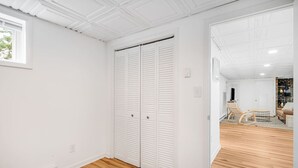 Ein Zimmer mit Holzboden, weißen Wänden und einem großen Kleiderschrank mit Schiebetüren.