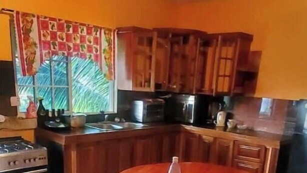 A kitchen with wooden cabinets, a gas stove, and a dining table with a stool. - Pvalley Suite 10B 1 Bedroom (Hatfield)