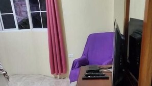 A room with a wooden desk, a television, and a purple chair. - Pvalley Suite 10B 1 Bedroom (Hatfield)