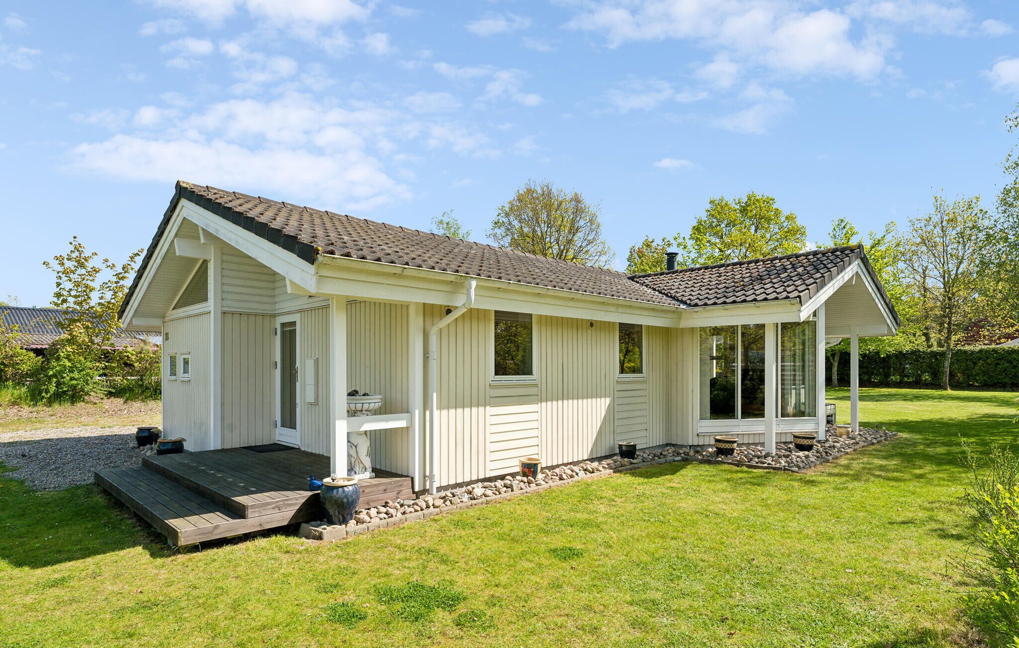 A single-story house with a porch, a small deck, and a garden area.