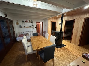 A dining area with a wooden table and chairs, a built-in stove, and a cozy seating area with cushions.