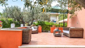 Eine Terrassengaststätte mit Korbmöbeln, Blumentöpfen und einem gefliesten Boden.