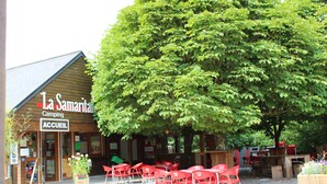 A wooden building with a sign reading "La Samaritaine Camping ACCUEIL" and outdoor seating with red chairs and tables. - Gîte ô Naturel - nature and comfort getaway (Buzancy)