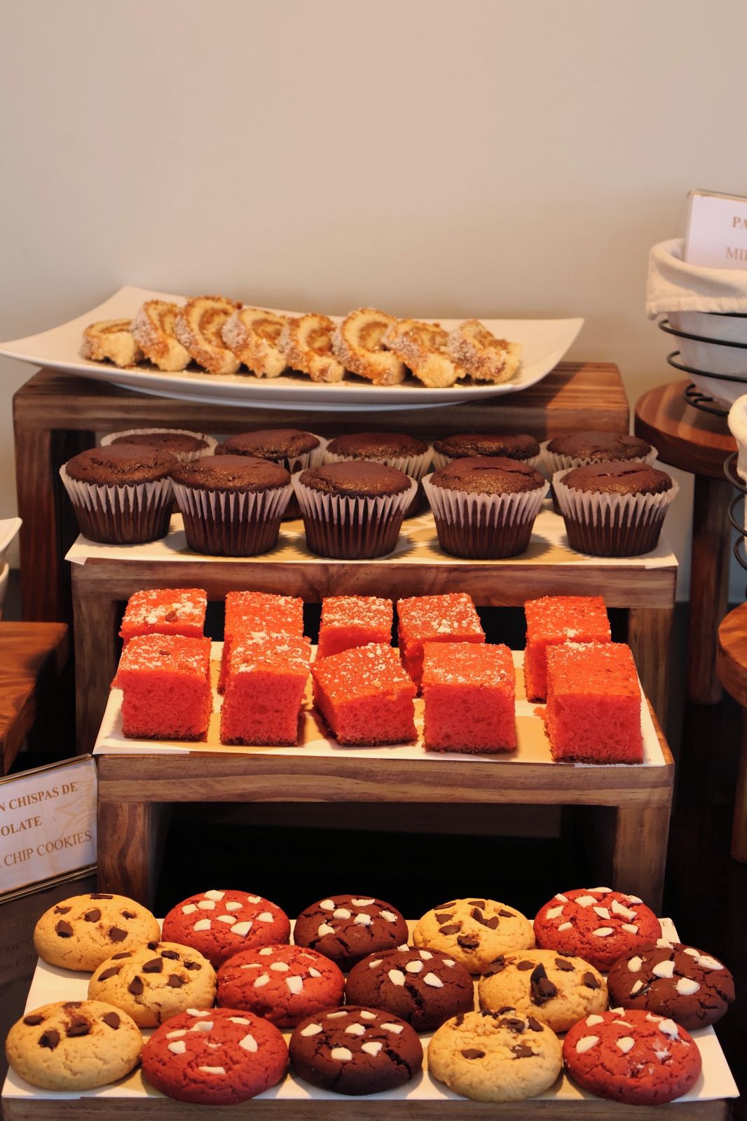 A display of various baked goods including muffins, chocolate chip cookies, and a plate of chocolate chip cookies.