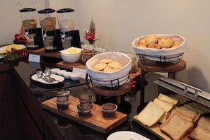 A breakfast buffet with various food items and utensils. - Hotel Maywa (Santa Cruz)