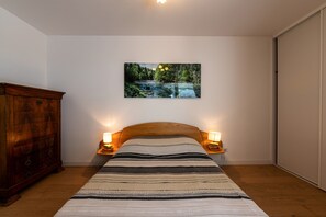 Une chambre à coucher avec un lit, deux lampes de chevet, une commode en bois et un tableau accroché au mur.