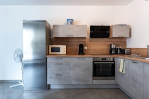 Une cuisine moderne équipée d’un réfrigérateur, d’un four à micro-ondes et d’un four en acier inoxydable, ainsi que d’un plan de travail en bois.