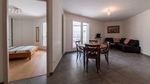 Une chambre avec un lit, une table à manger et des chaises, un canapé et un balcon avec vue.