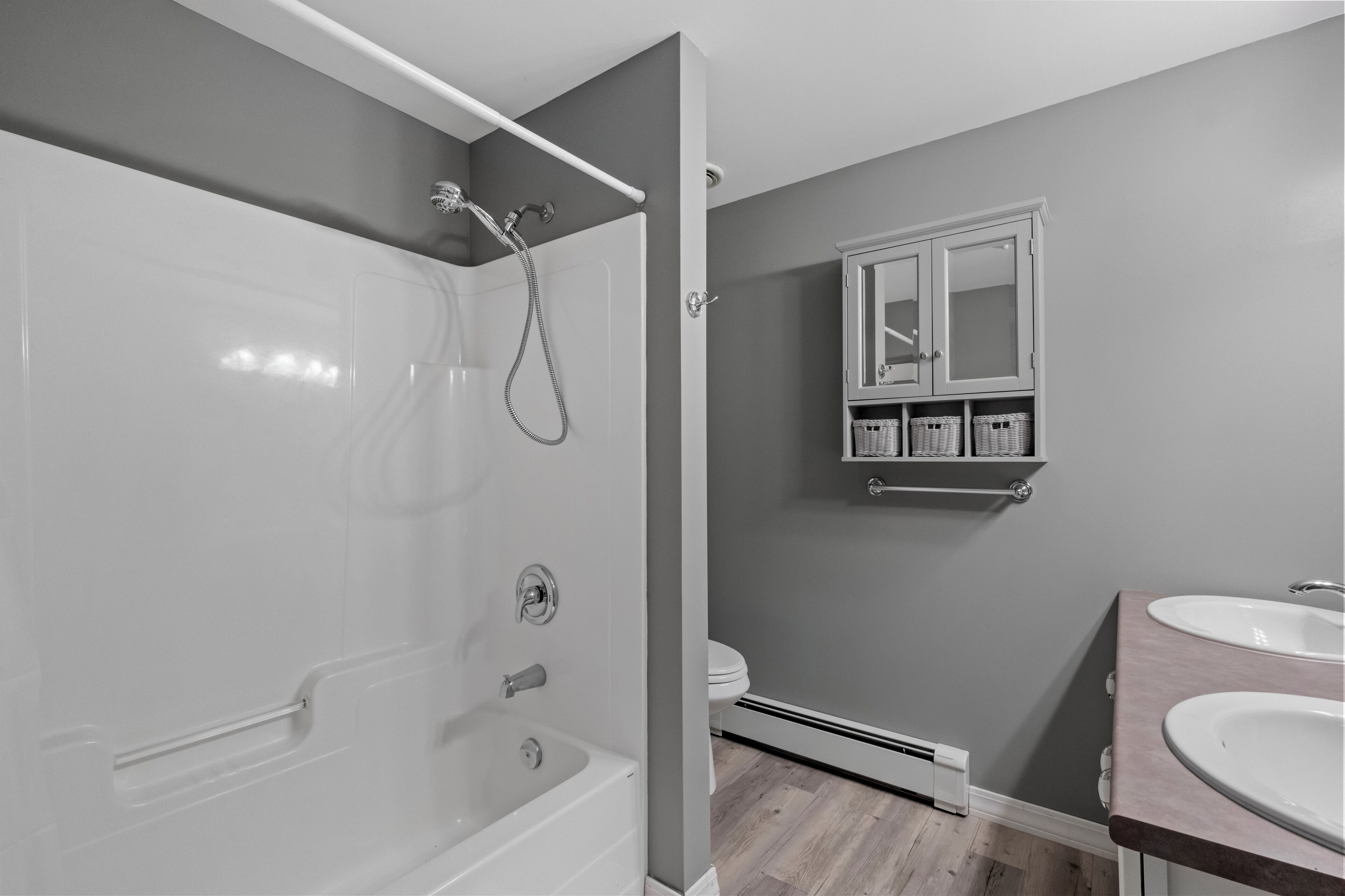 A modern bathroom with a walk-in shower, a toilet, and a vanity with two sinks.