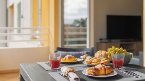 Une table de petit-déjeuner avec des croissants, un bol de raisins et deux verres de jus de fruits.