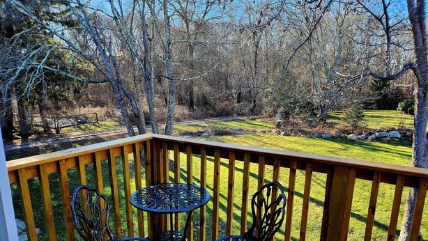 A wooden deck with two metal tables and chairs, overlooking a grassy yard with trees. - New for 2026. Private driveway and new private entrance. (Mystic)