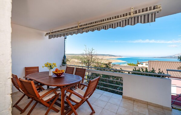 Enjoy a serene coastal view from this balcony with a table and chairs.