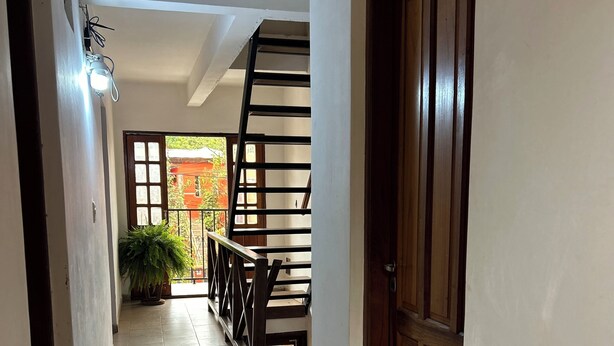 A hallway with tiled flooring, a wooden door labeled "1C", and a staircase leading to an outdoor area with a view of a red building.