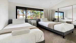 Ein Hotelzimmer mit zwei Betten, einem kleinen Tisch und einem Spiegel.