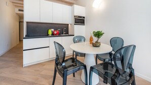 A modern kitchen with white cabinets, a black countertop, and a round dining table with four chairs. - Apartment 'Flat 3' with Lake View, Wi-Fi and Air Conditioning (Salò)