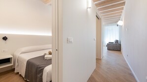 A modern hotel room with a bed, bedside table, and a view of a living area. - Apartment 'Flat 3' with Lake View, Wi-Fi and Air Conditioning (Salò)