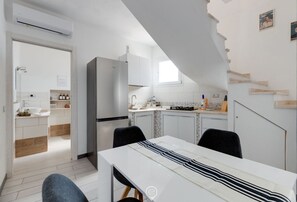 Una cocina moderna con armarios blancos, horno empotrado y un comedor con mantel a rayas.