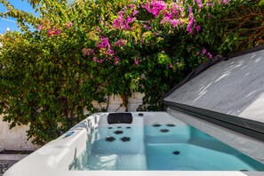Ein Whirlpool mit freiem Blick auf die Wasserstrahlen, umgeben von üppigem Grün und rosa Blüten.