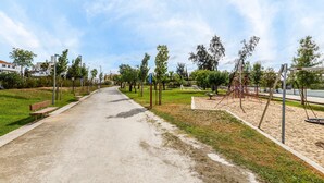 A paved pathway with benches, trees, and playground equipment. - Holiday Home 'Alojamento Local Coruche Erra' with Lake View, Wi-Fi and Air Conditioning (Coruche)