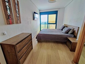 Une chambre à coucher avec un lit, une commode, une table de chevet et une fenêtre donnant sur un beau paysage.
