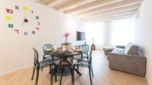 A modern living space with a dining area, a sofa, and a wall clock. - Apartment 'Flat 4' with Lake View, Wi-Fi and Air Conditioning (Salò)