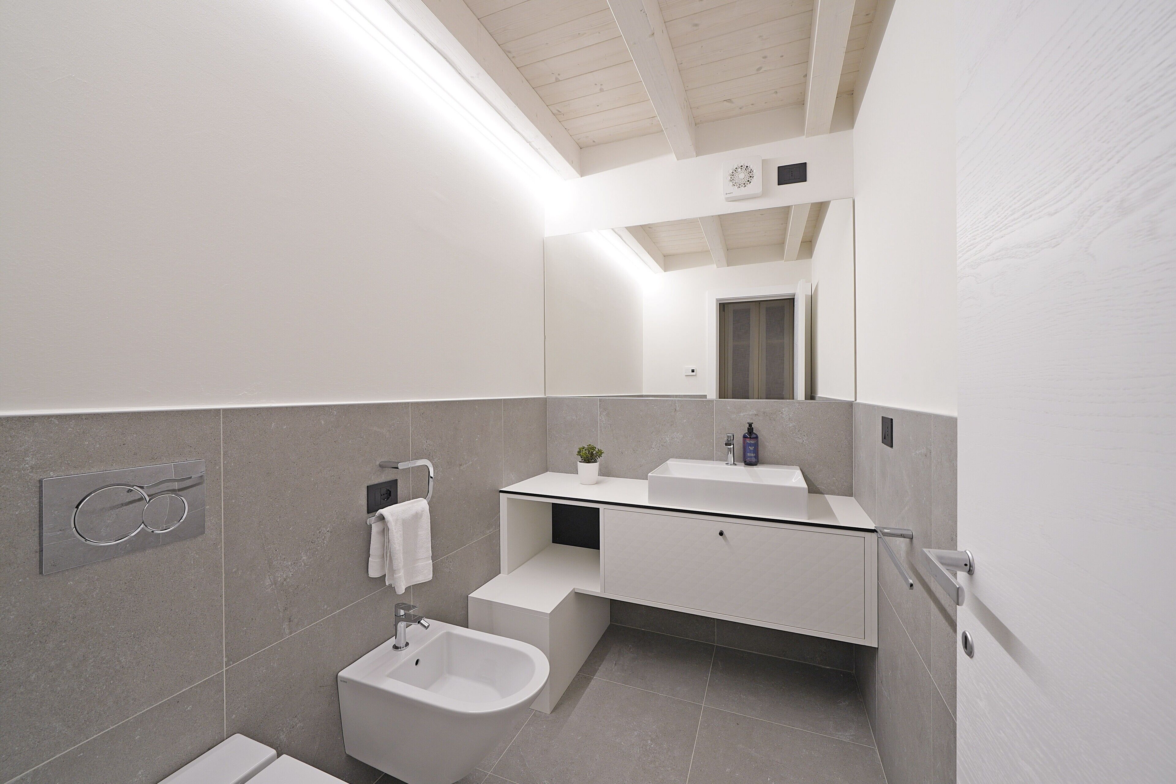 Ein modernes Badezimmer mit einer Bidet, einem Waschbecken und einem Spiegel.