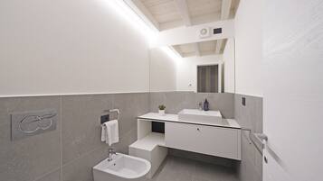 Ein modernes Badezimmer mit einer Bidet, einem Waschbecken und einem Spiegel.
