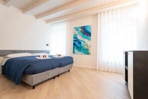 Een slaapkamer met een bed, een schilderij, een kledingkast en een raam met gordijnen.