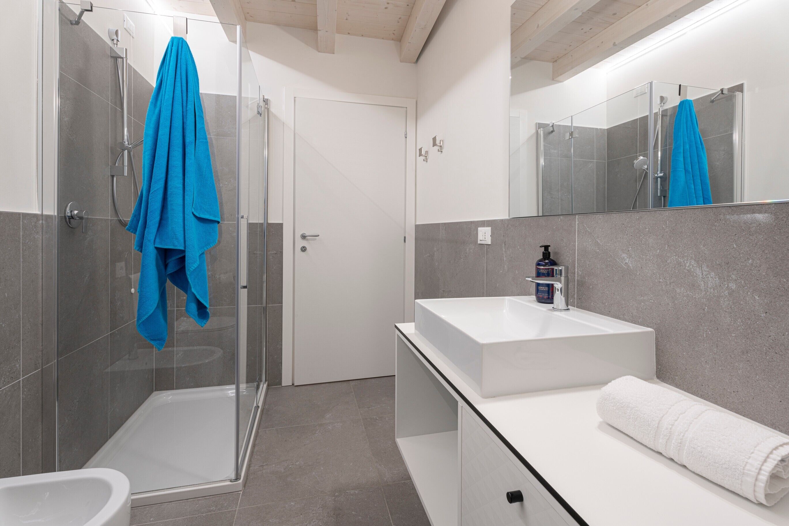 Ein modernes Badezimmer mit Duschkabine aus Glas, Waschbecken in Weiß und Toilette in Weiß.