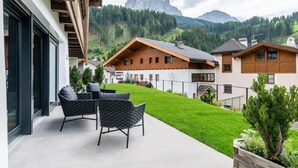 Ein modernes Gebäude mit Balkon, Holzfassade und Bergblick.