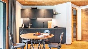 Eine moderne Küche mit dunklen Schränken, einer Holzbalkendecke und einem Essbereich mit rundem Tisch und Stühlen.