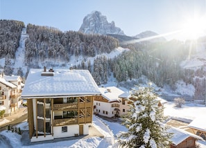 Bergresort bedekt met sneeuw, met een gebouw in chaletstijl, een skilift en een imposante bergtop op de achtergrond.