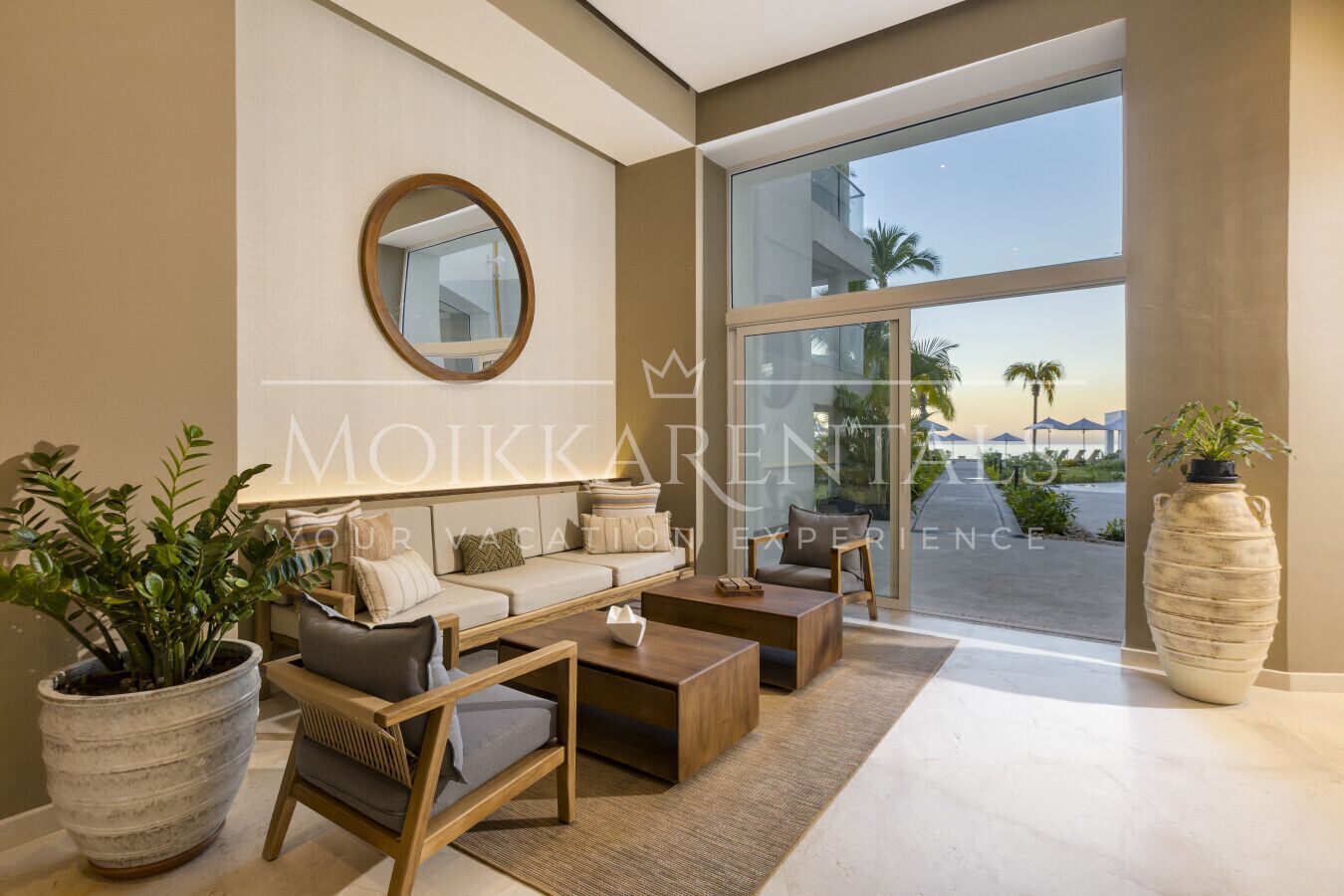 A modern living room with a sofa, coffee table, and chairs, a large mirror, and a view of the outside.