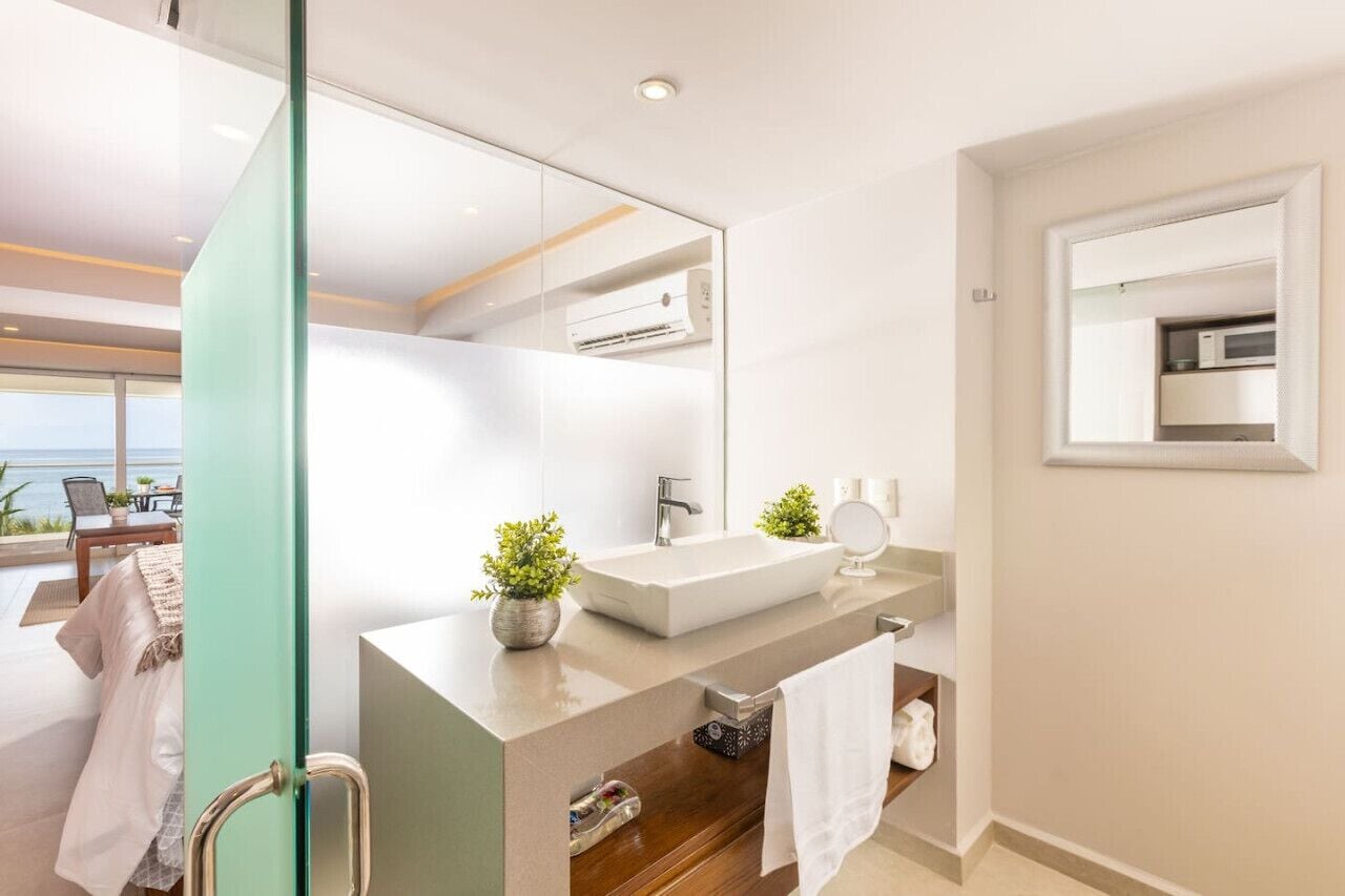 Un bagno moderno con uno specchio grande, un lavandino bianco e un mobile contenitore in legno.