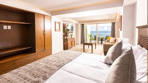A hotel room with a bed, a wooden wardrobe, a small table, a sofa, and a balcony with a view of the sea. - Serene Beachfront Escape – Includes Delicious Breakfast (Puerto Vallarta)