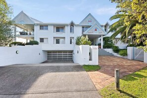 A modern two-story house with a garage, a covered porch, and a well-maintained lawn. - Spinnakers Reach Unit 9 (Batemans Bay)