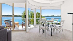 Una habitación moderna con un ventanal de vidrio que da a un balcón con vistas a un lago.