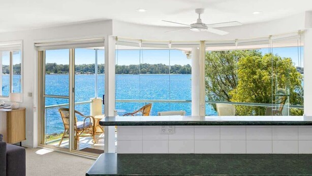Una cocina moderna con vistas a un lago, grandes ventanales y un ventilador de techo.