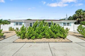 Il s’agit d’un bâtiment d’un seul étage, doté d’un toit plat, de murs extérieurs blancs et de volets bleu clair. Devant le bâtiment se trouve un jardin bien entretenu, avec des arbustes verts et un chemin de gravier.