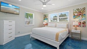 A bedroom with a bed, a TV, a ceiling fan, and artwork on the walls. - Modern 2BR-Hot Tub/Pergola/Games (West Palm Beach)