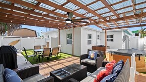 An outdoor patio with wicker furniture, a hot tub, and a pergola with a ceiling fan. - Modern 2BR-Hot Tub/Pergola/Games (West Palm Beach)