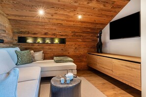 Un salon moderne avec un plafond en bois, un canapé, une table basse, un téléviseur et un meuble en bois.