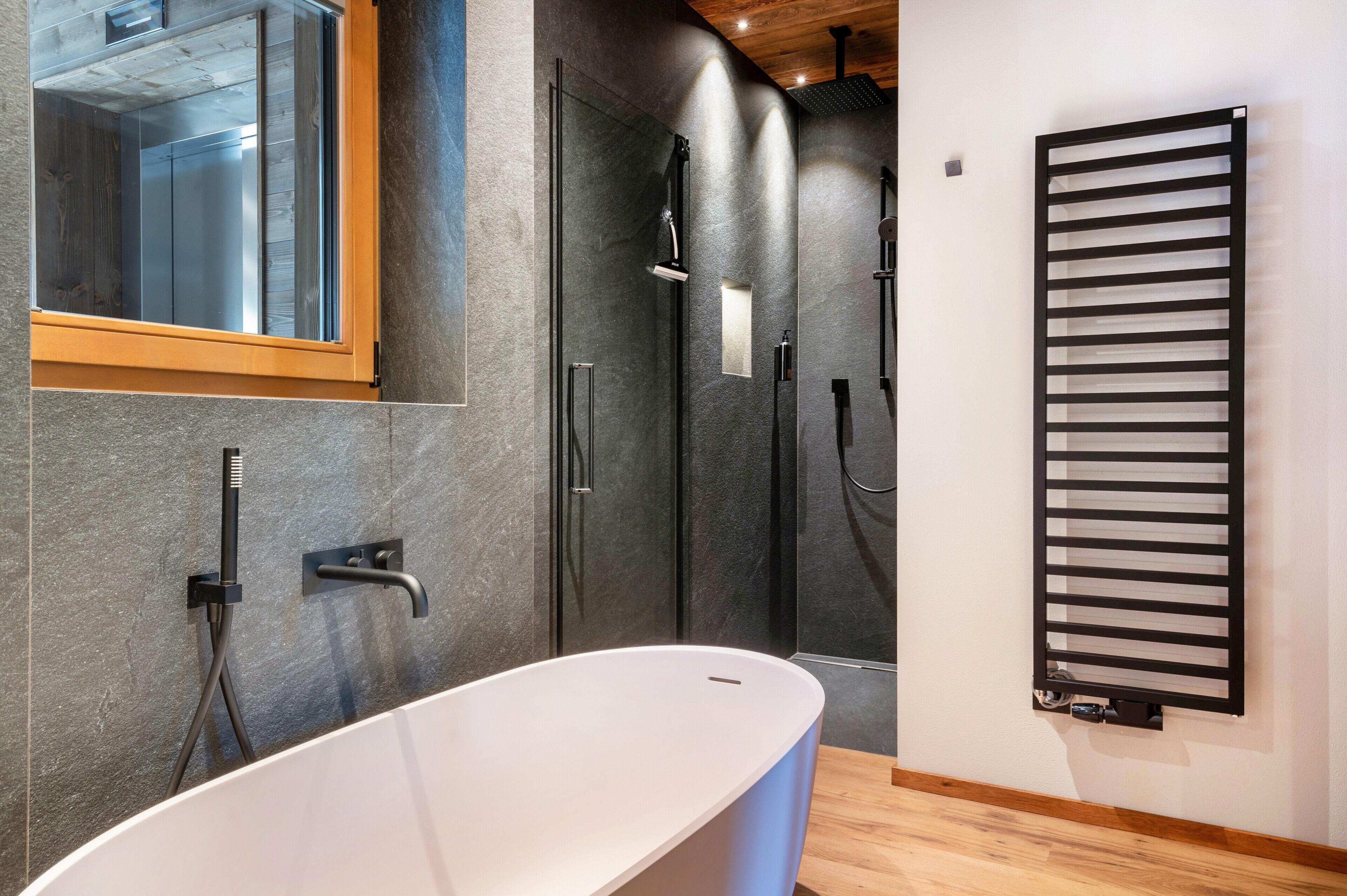 A modern bathroom with a freestanding bathtub, a glass shower enclosure, and a wall-mounted towel rack.