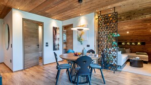 Un intérieur moderne avec un plafond en bois, une table à manger ronde entourée de chaises, un canapé et un élément de séparation décoratif.
