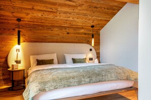 Un plafond en bois, un lit avec une literie blanche et deux lampes de chevet.
